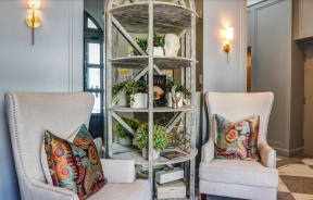 a living room with two chairs and a shelf with plants