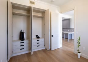 a walk in closet with white cabinets and drawers and