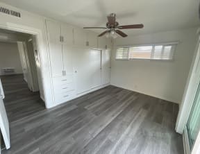an empty room with white cabinets and a ceiling fan