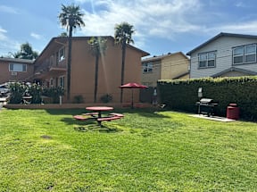 A red picnic table is in the middle of a green lawn.