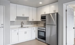 a white kitchen with stainless steel appliances and white cabinets
