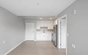 A kitchen with white cabinets and appliances in a room with white walls.