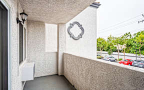 A balcony with a white wall and a decorative element above a door.