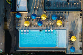 A pool surrounded by yellow and blue umbrellas.