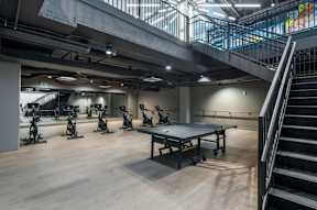A room with a table, chairs and exercise bikes.