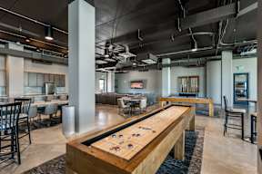 A shiny pool table is in the middle of a room with a bar and chairs.