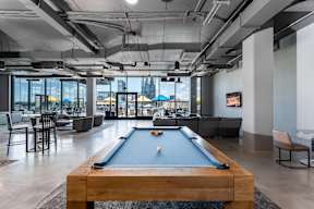 A pool table is in the middle of a room with a view of the city.