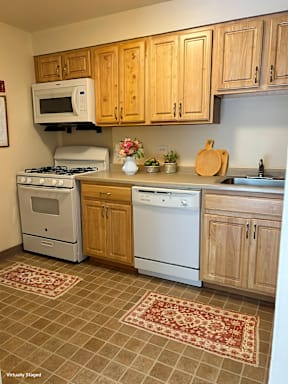 A kitchen with a white stove and oven, a microwave, and wooden cabinets.