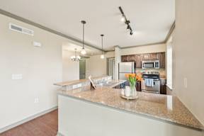 A kitchen with a granite countertop and a vase of flowers on it.