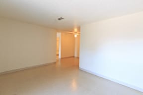 an empty living room with white walls and a beige tiled floor