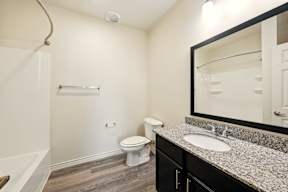 A bathroom with a toilet, sink, and mirror.