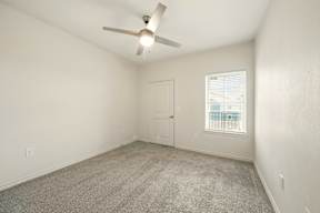 A room with a ceiling fan and carpeted floor.