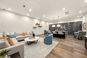 A modern living room with a grey rug and a grey sofa with orange and blue pillows.