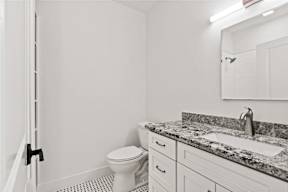 A white bathroom with a toilet, sink, and mirror.