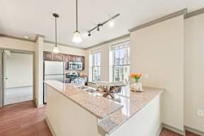 A kitchen with a granite countertop and pendant lights.