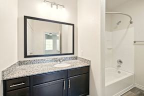 A bathroom with a sink, mirror, and bathtub.