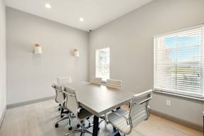 A conference room with a table, chairs, and a window with blinds.