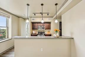 A kitchen with a large island and pendant lights.
