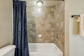 A white bathtub with a blue shower curtain in a bathroom.