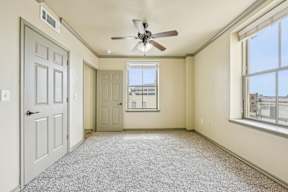 A room with a ceiling fan and a window overlooking a cityscape.