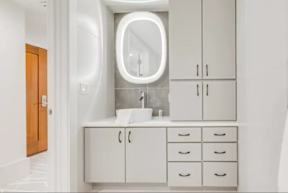 A bathroom with a sink, mirror, and cabinets.