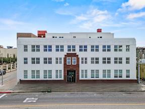 A white building with a red door and windows on the side.