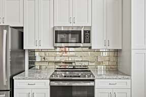 A kitchen with white cabinets and a stove top oven.