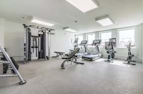 A spacious gym with a variety of equipment including treadmills, elliptical machines, and weight machines.
