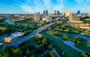 a river flows through a park with a city in the background