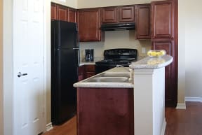a kitchen with a black refrigerator freezer next to a stove top oven