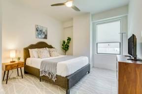 A bedroom with a large bed, a television, and a window.