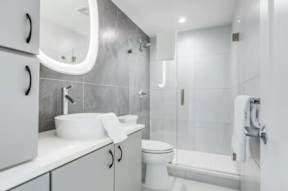 A white bathroom with a sink, toilet, and shower.