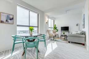 A living room with a white couch, a black TV, and a dining table with chairs.
