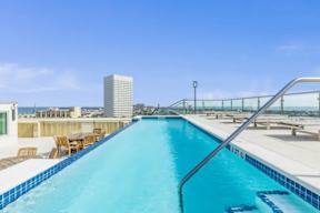 A swimming pool on a rooftop with a glass railing.