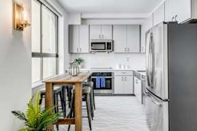 A modern kitchen with a wooden table and stainless steel appliances.