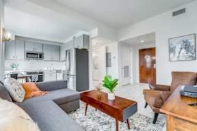 A living room with a grey couch, a wooden coffee table, and a brown leather chair.