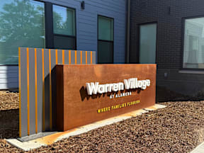A sign that says Warren Village at Alameda with a brown background.