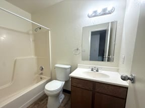 A white toilet sits next to a white sink in a small bathroom at Willow Grove Apartments, Clifton, Colorado, 81520.