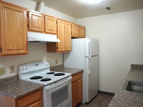 A kitchen with a white stove and refrigerator at Grand Manor Apartments, Grand Junction, Colorado