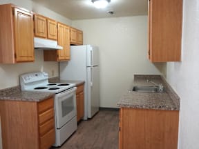 A kitchen with a white stove and refrigerator at Grand Manor Apartments, Grand Junction