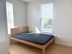 A bed with a black mattress is in a room with a window.