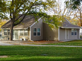 A house with a tree in front of it at Grand Manor Apartments, Grand Junction, CO, 81501.