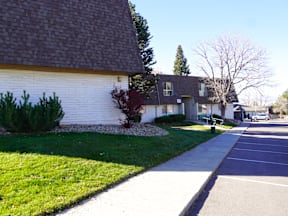 A white house with a brown roof and a green lawn at Mountain Terrace Apartments, Colorado.