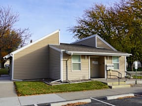 A small house with a grey roof and a brown wall at Grand Manor Apartments, Grand Junction, CO