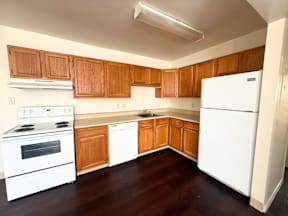 A kitchen with white appliances and wooden cabinets at Townview Plaza Apartments, Denver, CO, 80204.