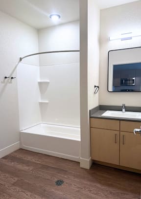 A bathroom with a white tub and brown flooring.