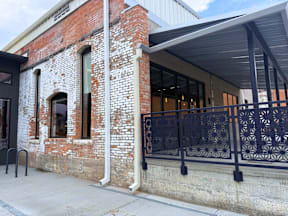 A brick building with a black iron fence in front.