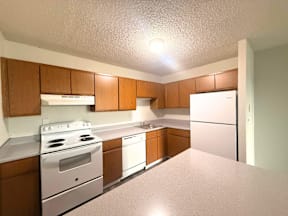 A kitchen with white appliances and wooden cabinets.