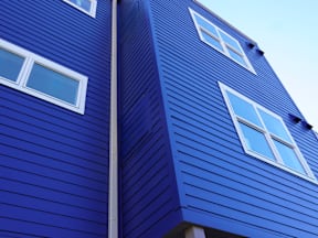 A blue wooden building with white windows at Gateway Village Apartments, Fort Morgan