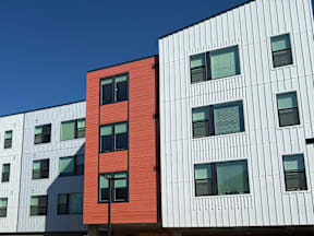 A red building stands out next to white buildings with black windows.